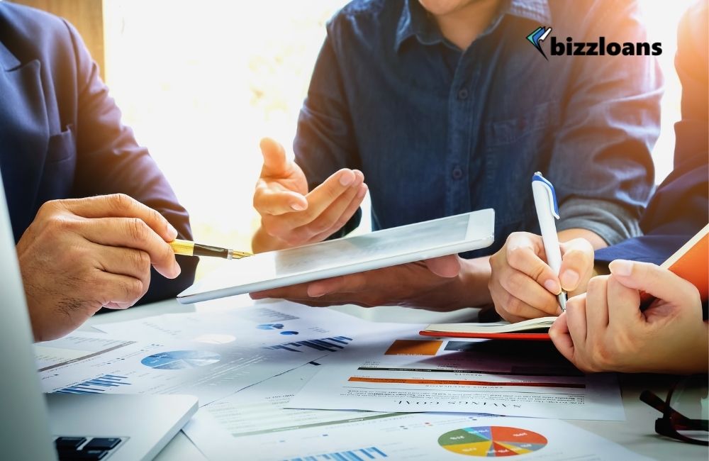how-to-improve-your-businesss-financial-position business owners discussing on how to improve their financial position while holding a tablet