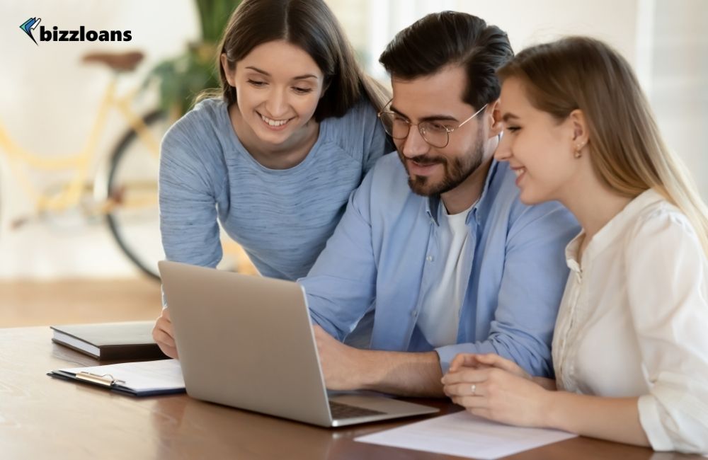 10-best-referral-program-examples-for-your-small-business-11 three young business owners looking for referral programs on laptop