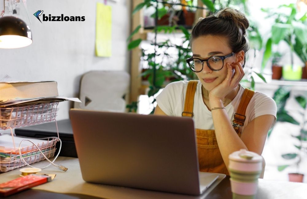 how-to-choose-the-best-loan-for-your-small-business Young female business owner in glasses using laptop looking for the best small business loans online