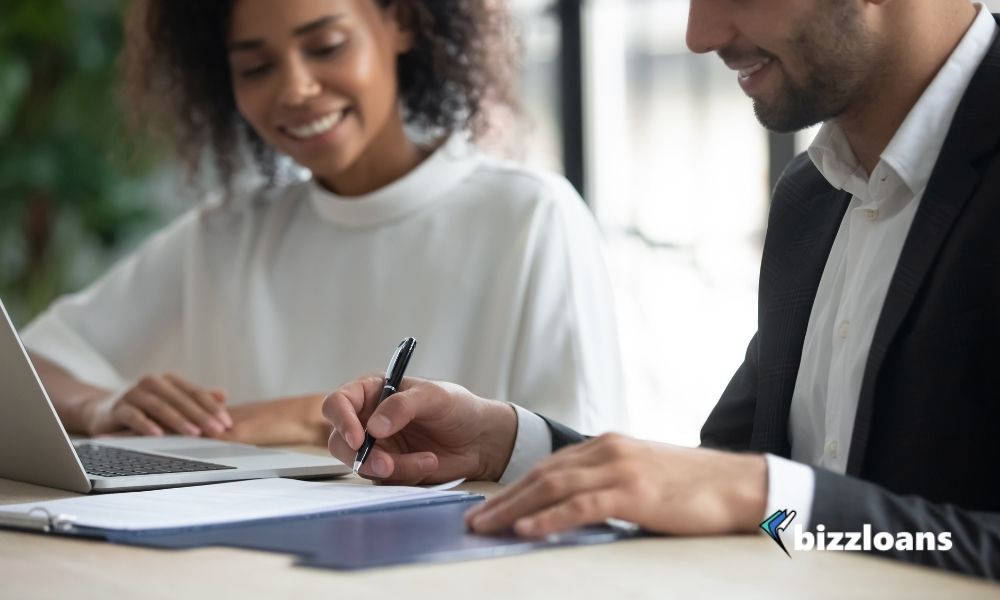 what-is-cash-flow-lending-definition-pros-and-cons happy business owner signing for a cash flow lending with a female broker